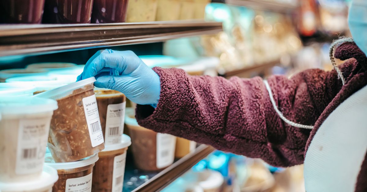 Person reading a nutrition label on a food package, highlighting serving size, %Daily Value, and added sugars